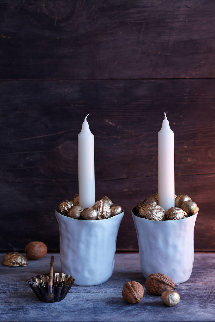 China cups filled with gold-painted nuts used as festive candlesticks