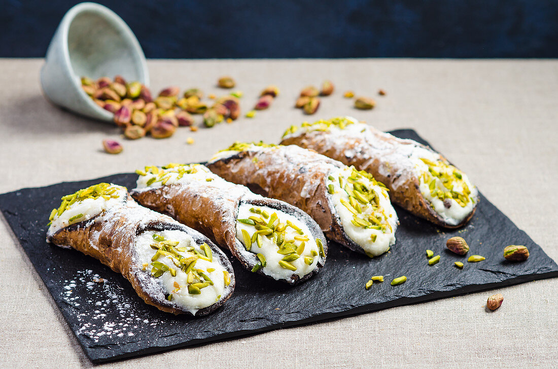 Italian sicilian cannoli with sweet ricotta cheese, chocolate chips and garnished with chopped pistachios and icing sugar