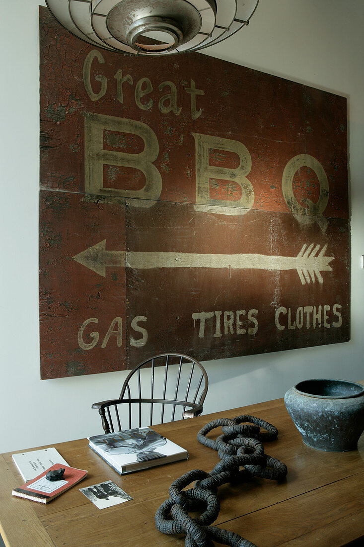 Old BBQ sign above artworks on wooden table