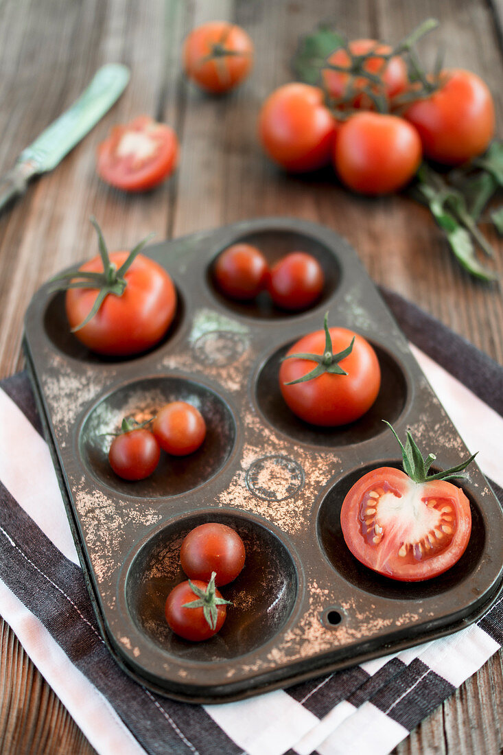 Tomaten in Metallform auf Holzuntergrund