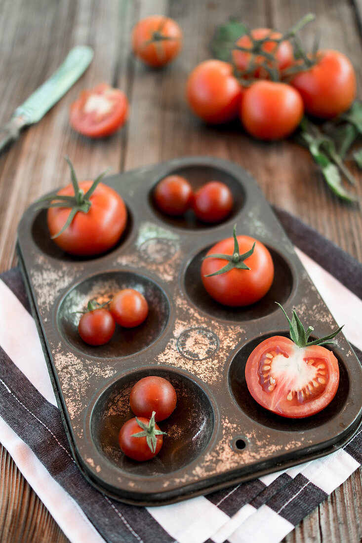 Tomatoes in a metal tray on a wooden background