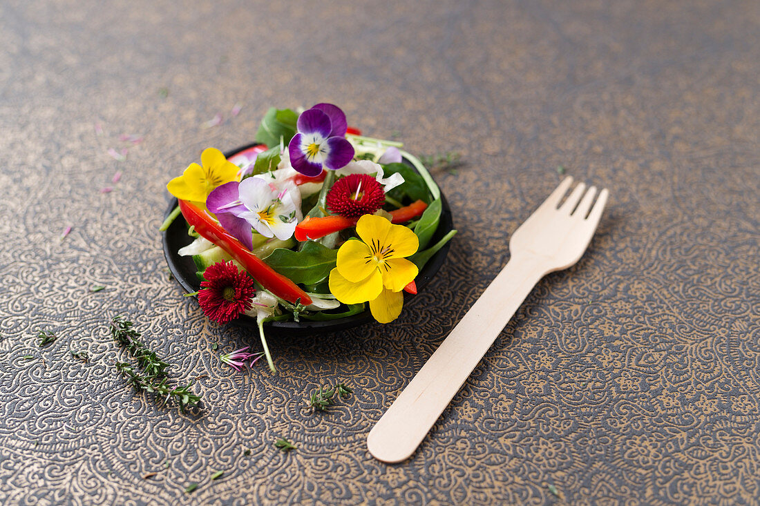 Rocket and cucumber salad with peppers, pine nuts and edible flowers