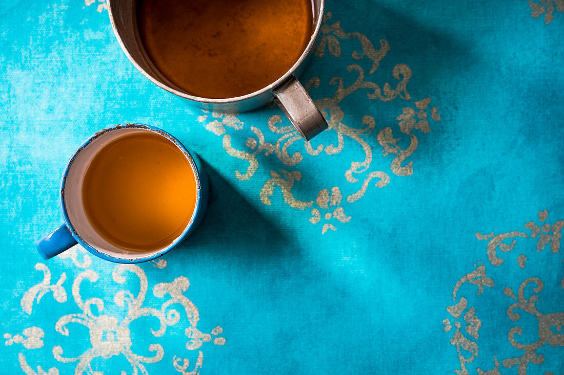 Koriander-Ingwer-Tee in Metalltassen auf azurblauem Untergrund