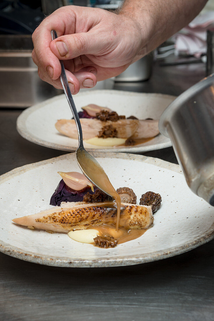 A chef drizzles sauce on a plate