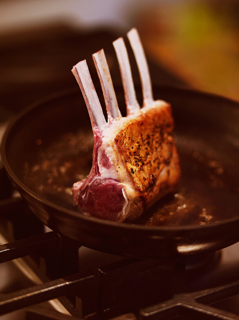 A rack of lamb in a pan on the stove