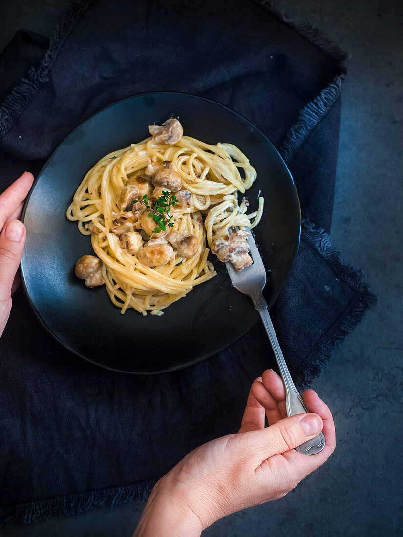 Frau isst Spaghetti mit Pilzsauce