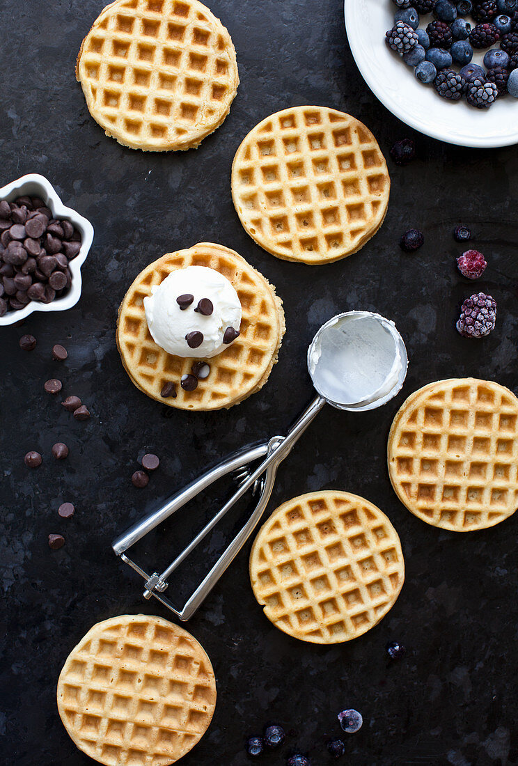 Waffeln, Eiscreme, Chocolatechips, Eisportionierer und gefrorene Beeren