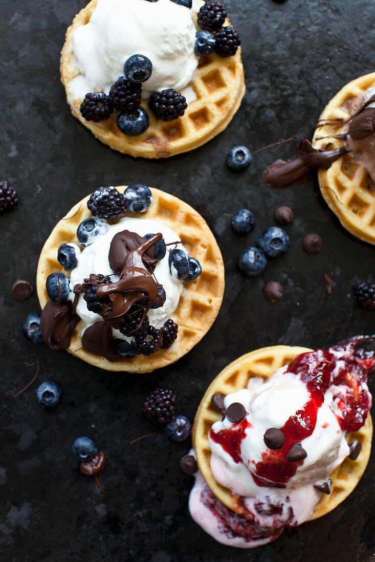 Waffles topped iwth ice cream, frozen berries, chocolate and strawberry jam
