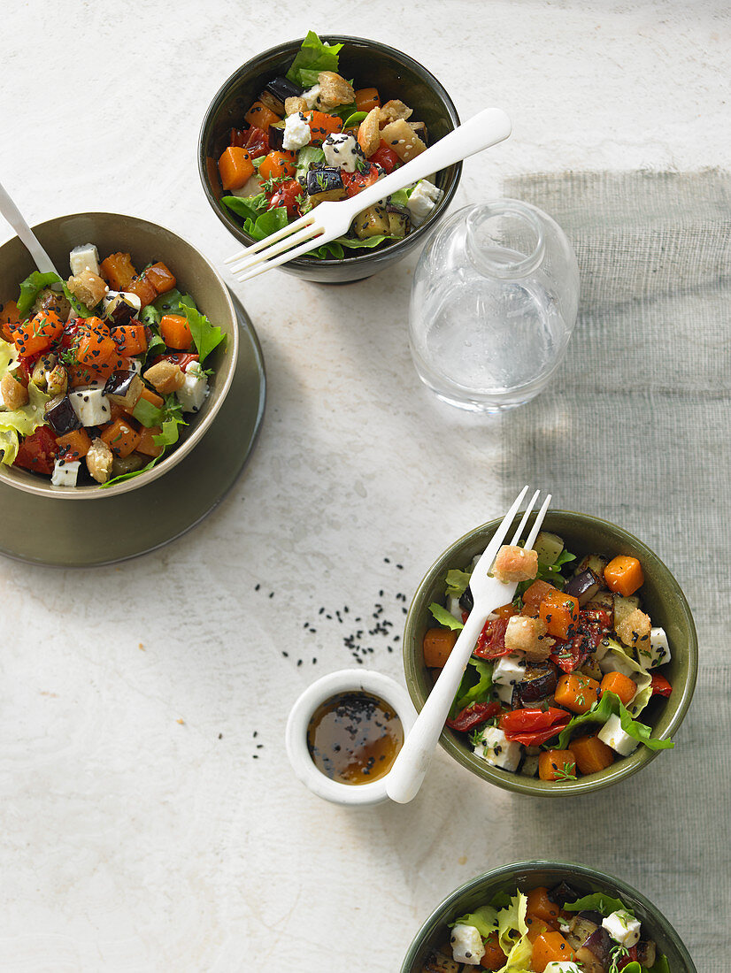 Gebratene Kürbiswürfel mit Aubergine, Schafskäse, getrockneten Tomaten, Oliven und Endiviensalat in schwarzem Sesamdressing