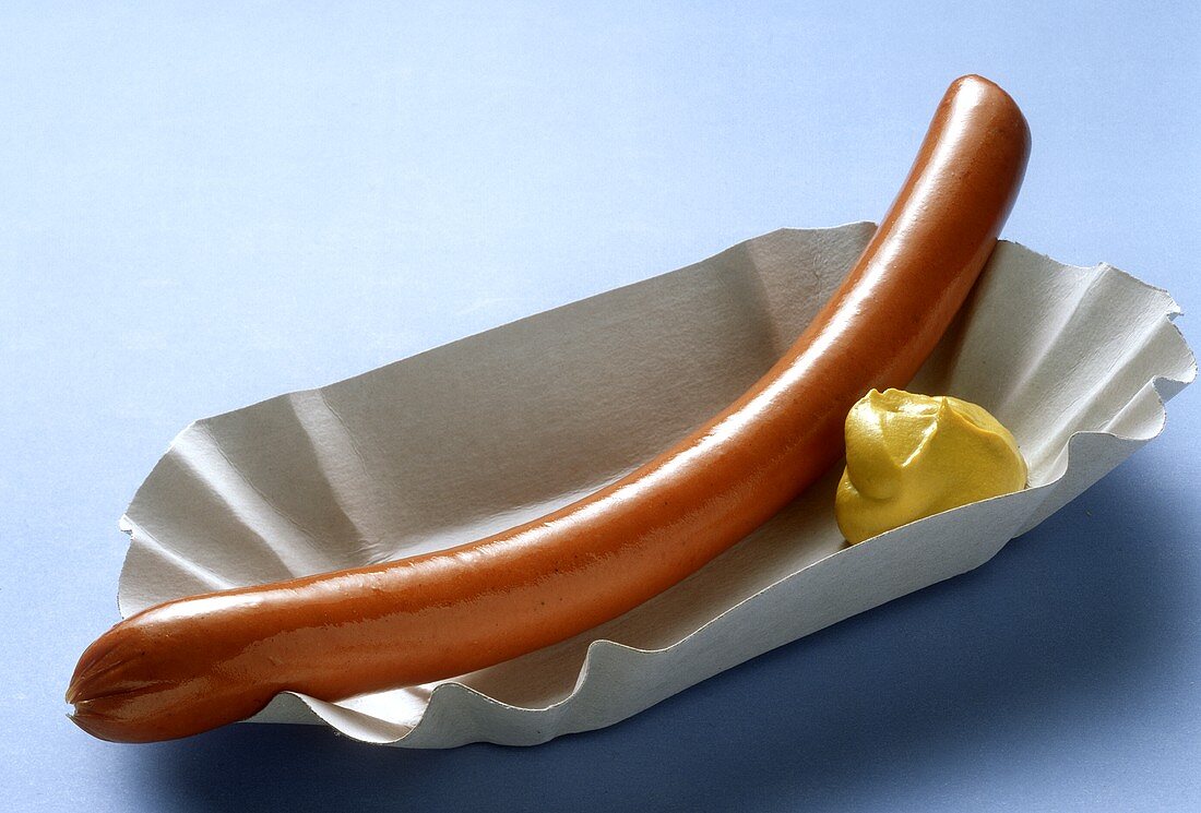 A sausage with mustard in paper tray