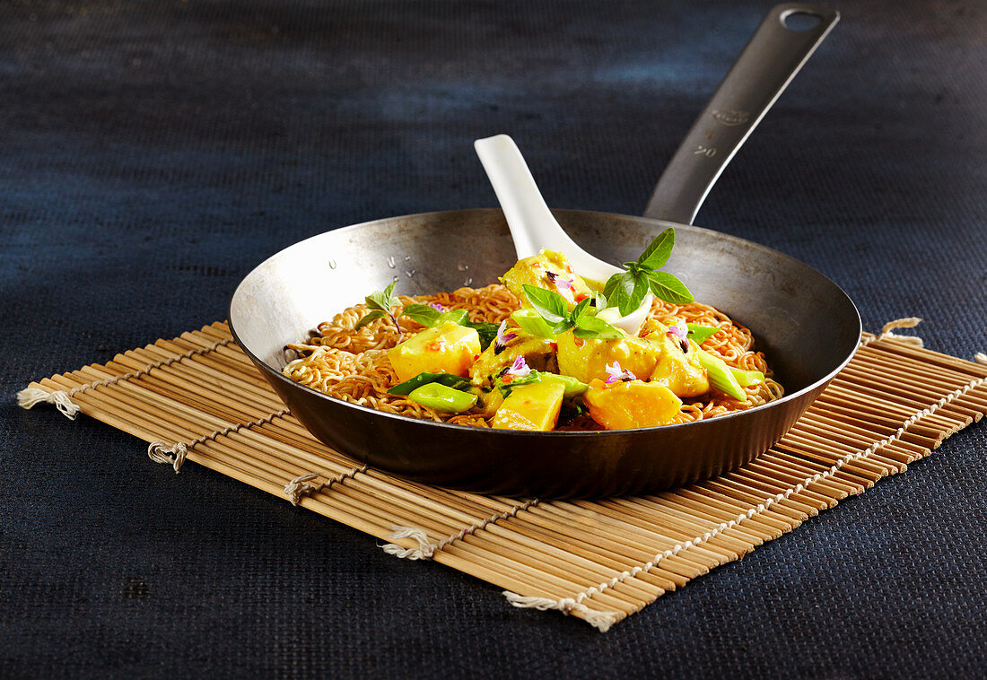 Grünes Mango-Hähnchen-Curry mit gebratenen Eiernudeln in der Pfanne