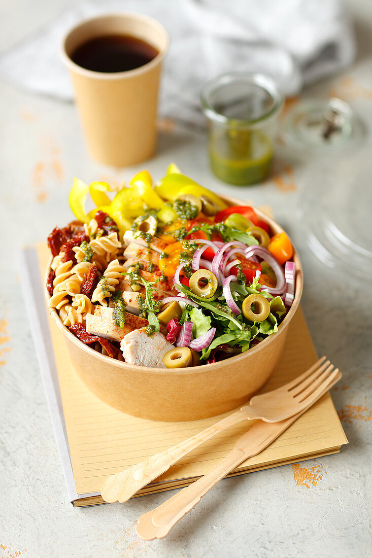 Pasta salad with chicken, dried tomatoes, vegetables and pesto