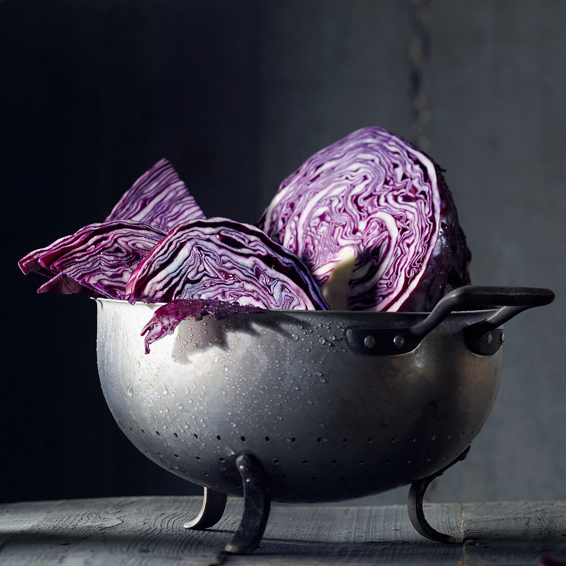 Red cabbage pieces with drops of water in an old metal colander