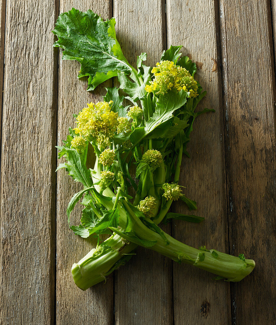 Rauke (Rucola) mit Blüten auf altem Holztisch