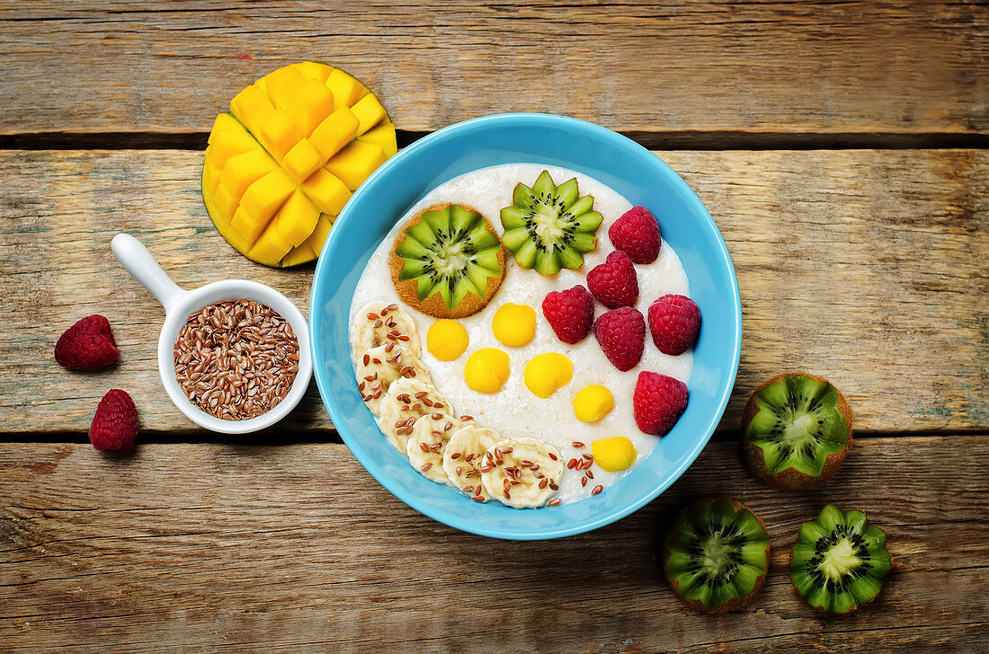 Breakfast oatmeal porridge with kiwi, mango, raspberry, banana and flax seeds