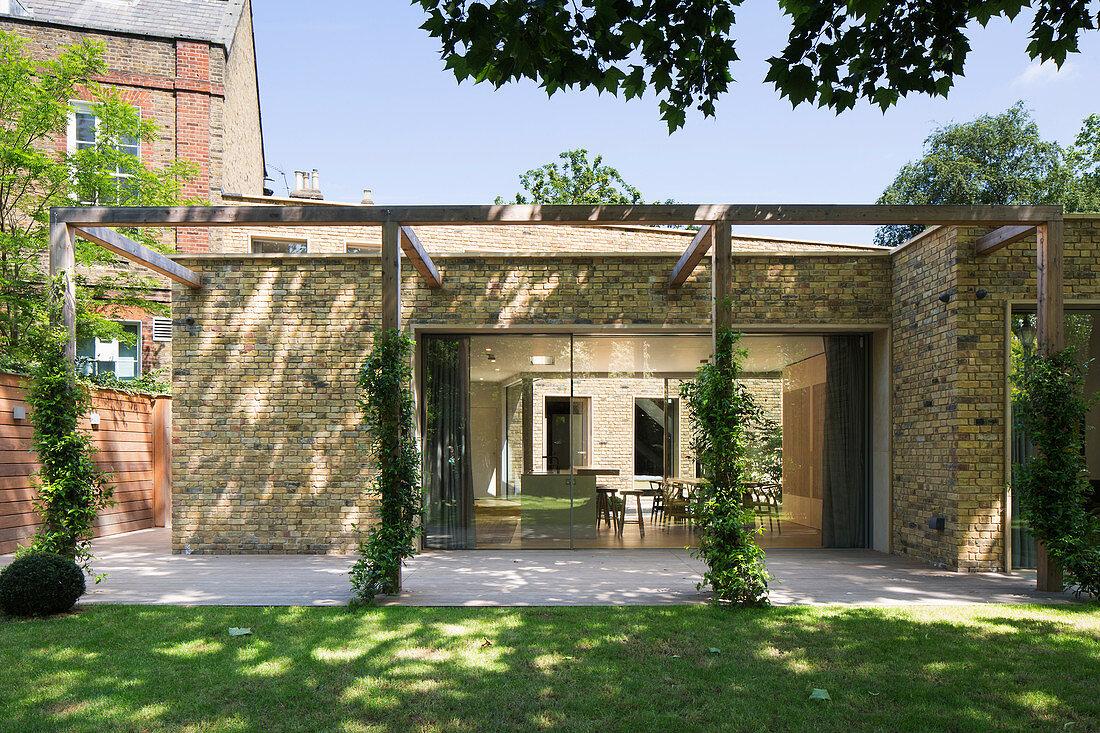 View into open-plan kitchen through pergola from garden