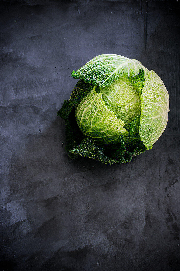 Whole savoy cabbage on a dark surface