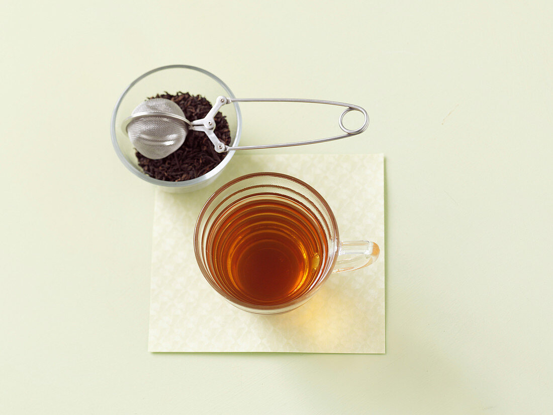 Pu-Erh Tee lose mit Teefilter und Aufguss im Glas