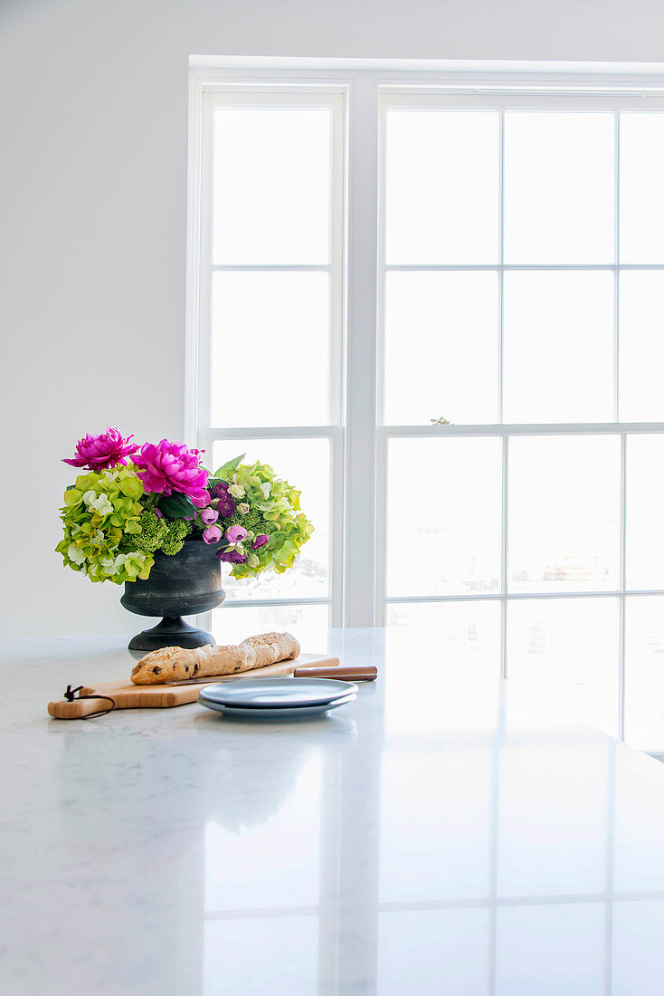 Bread and flower arrangement on worksurface in front of window
