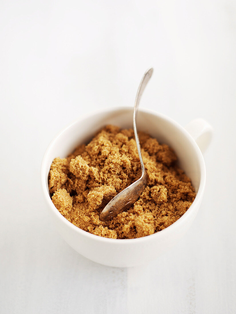 Brauner Zucker in Tasse mit Löffel