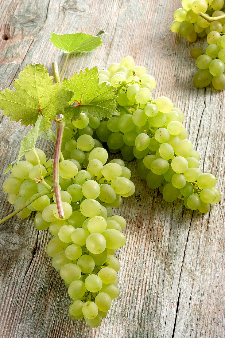 Grüne Weintrauben auf Holz mit Weinlaub