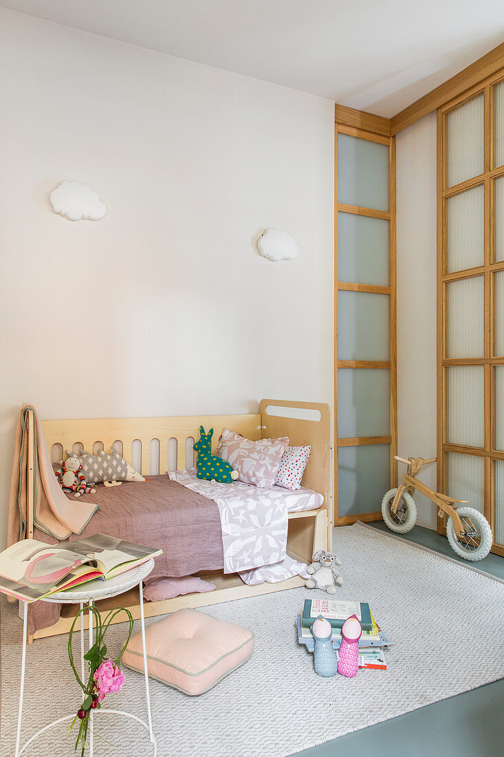 Bett und Laufrad im pastellfarbenen Kinderzimmer