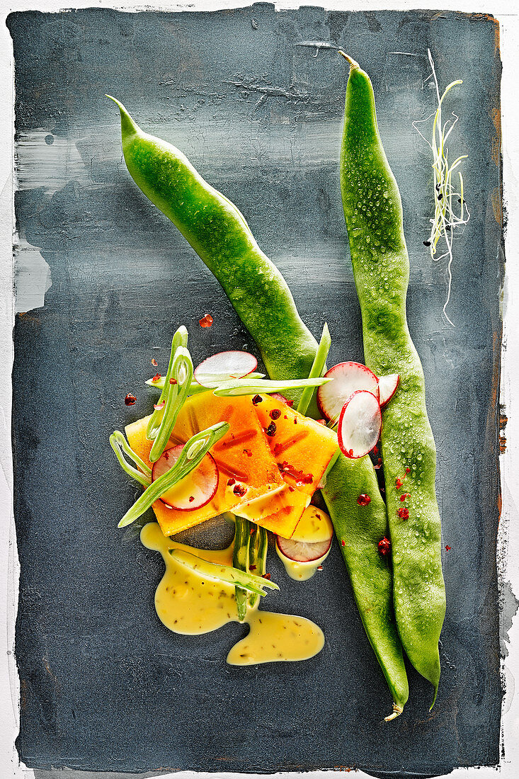 Food art: green beans with persimmon, radishes and mustard sauce