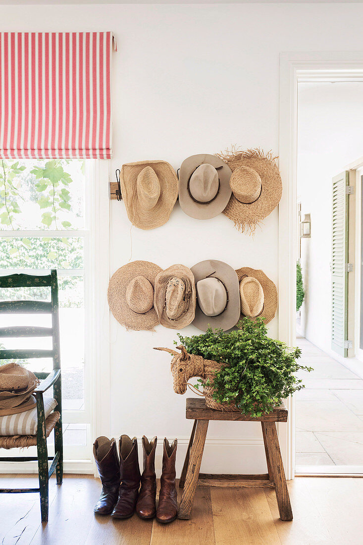 Hat collection on the wall above the stool with plants and boots