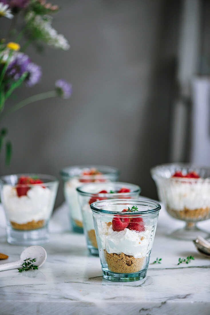 Dessert mit Keksboden, Mascarponecreme und Himbeeren in Gläsern serviert