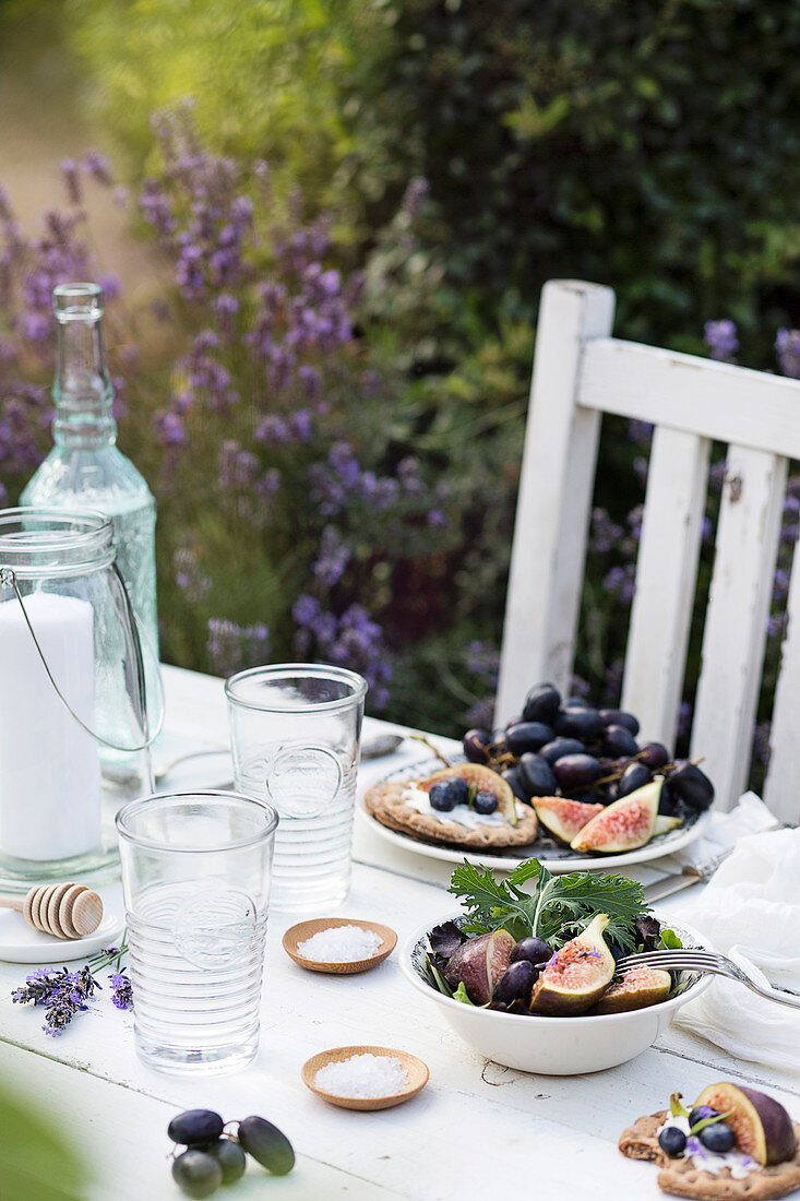 Gedeckter Tisch im sommerlichen Garten mit Obstsalat, Crackern und Getränk