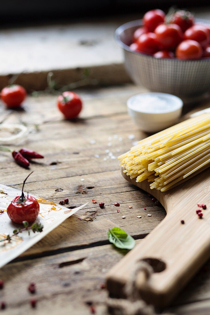 Zutaten für Pastagericht: Spaghetti, Tomaten und Peperoni auf rustikalem Holztisch