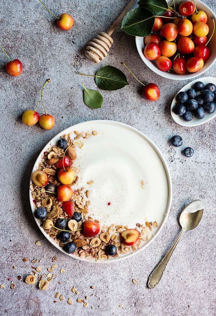 Yogurt and fresh summer fruit on grey background