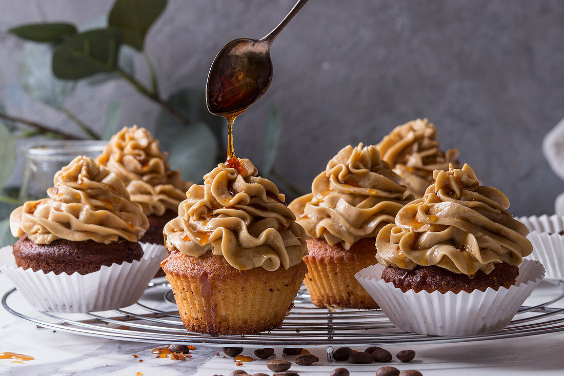 Fresh baked homemade cupcakes with coffee buttercream and pouring from spoon caramel