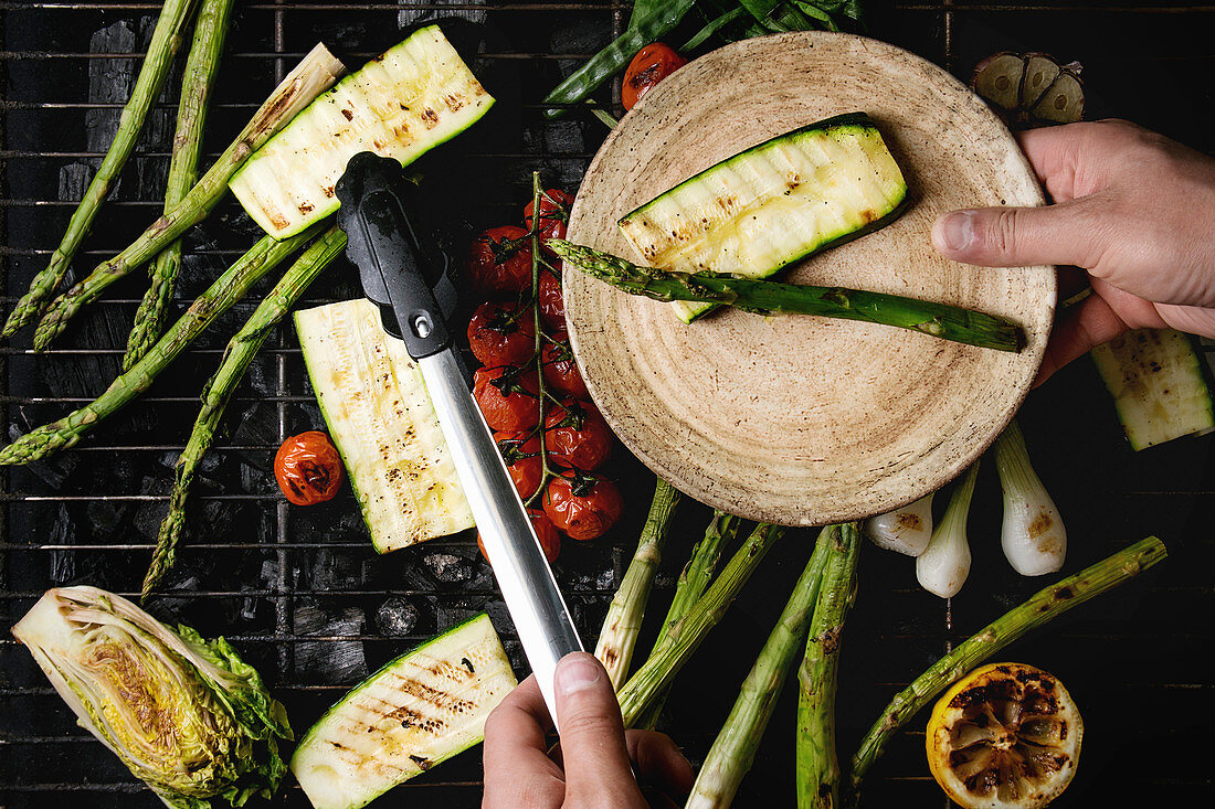 Grilled vegetables green asparagus, garlic, lemon, spring onion, zucchini, cherry tomatoes, salad on bbq grill rack over charcoal