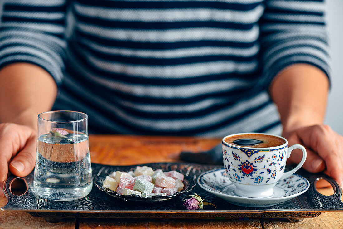 https://media02.stockfood.com/largepreviews/Mzg4NDU2NDQz/12530853-A-woman-serving-Turkish-coffee-in-a-traditional-Turkish-coffee-cup-on-a-traditional-copper-tray-a-glass-of.jpg