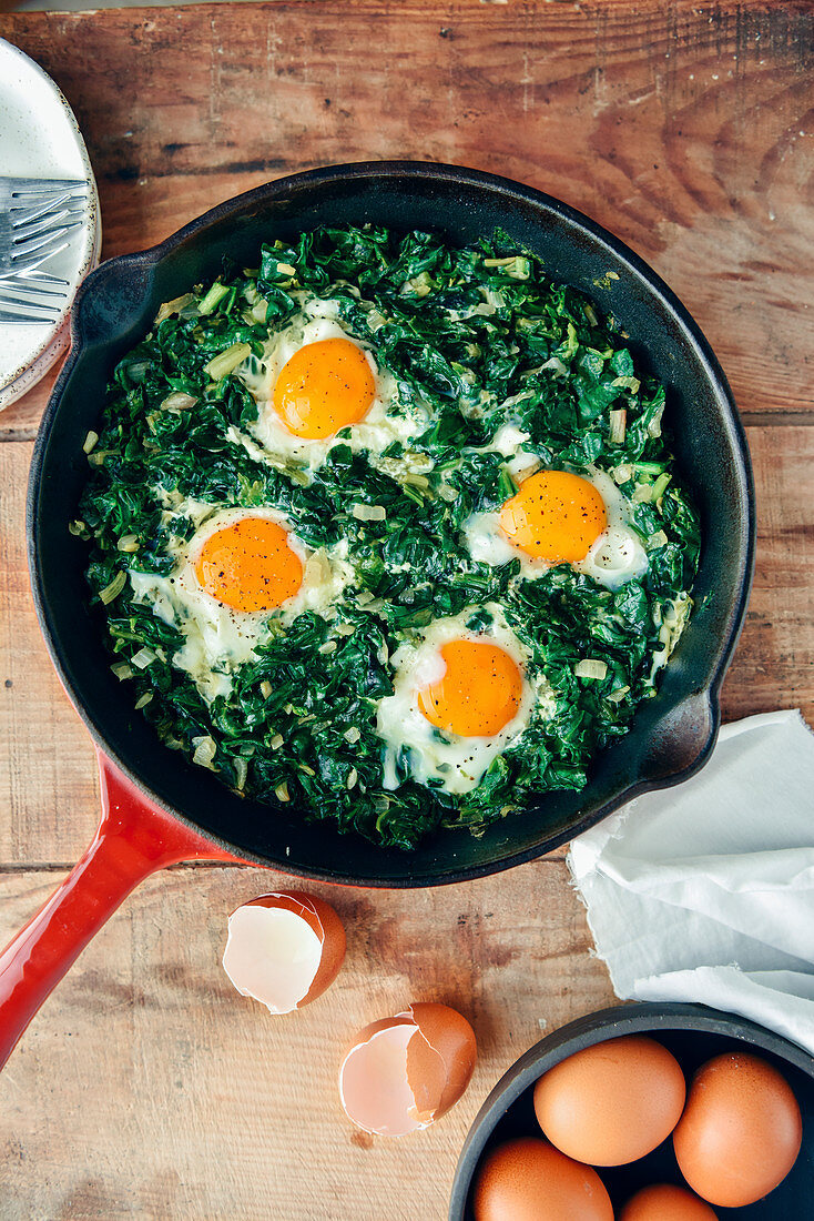 Spinach with eggs served in an iron pan