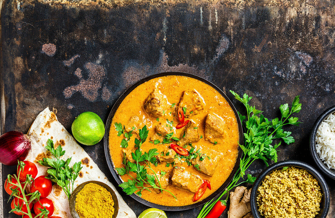Traditionelles indisches Curry mit Zutaten, Reis und Naan-Brot (Aufsicht)