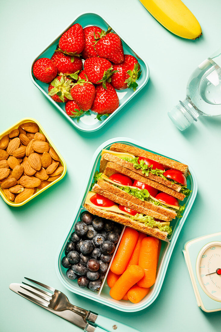 Creative flat lay with healthy lunch and office or school supplies on pastel colors background