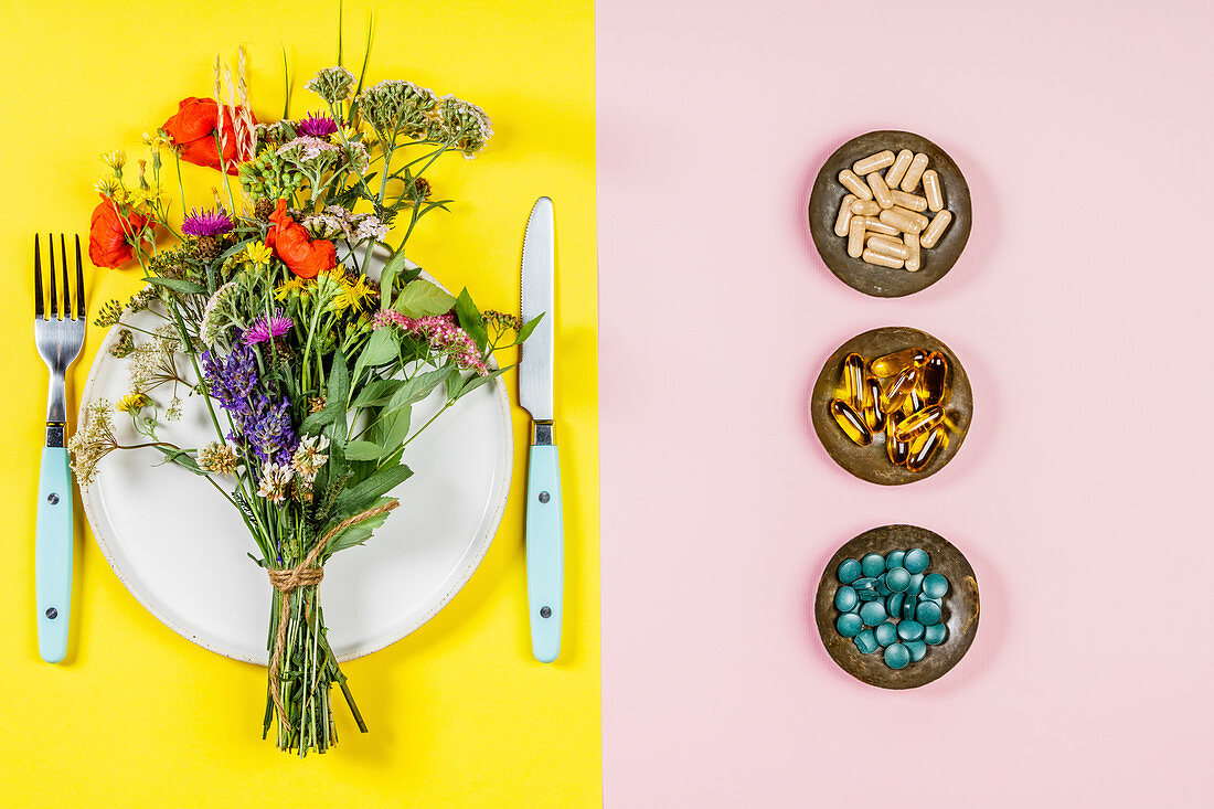 Symbolbild-Wildblumenstrauss auf Teller daneben Tabletten und Kapseln in Schälchen