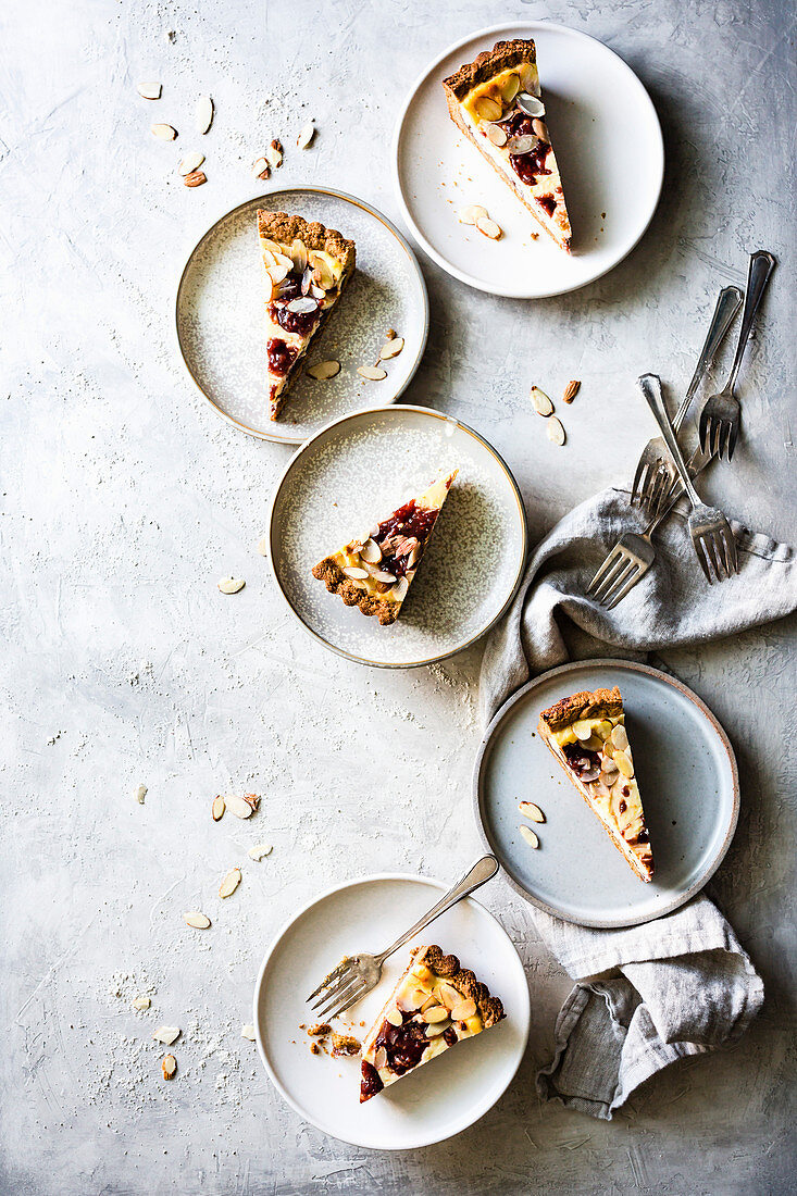 Mehrere Stücke Ricottakuchen mit mit Marmelade auf Tellern (Italien)