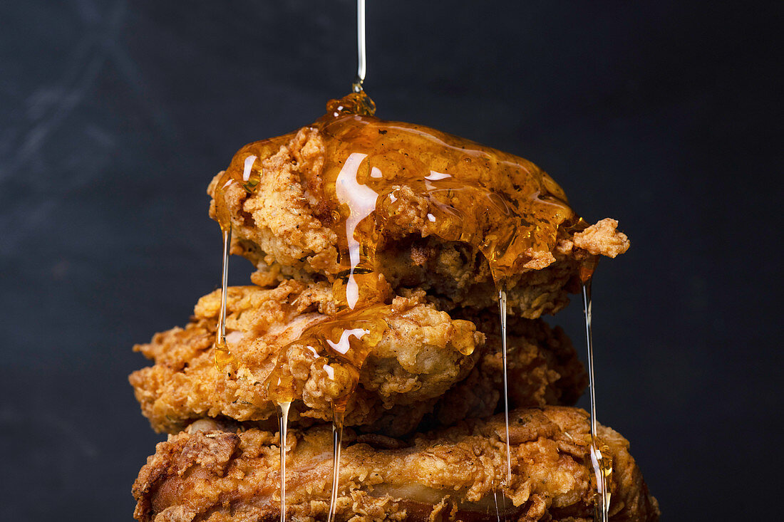 Honig fliesst auf Fried Chicken (frittierte Hähnchenteile, USA)
