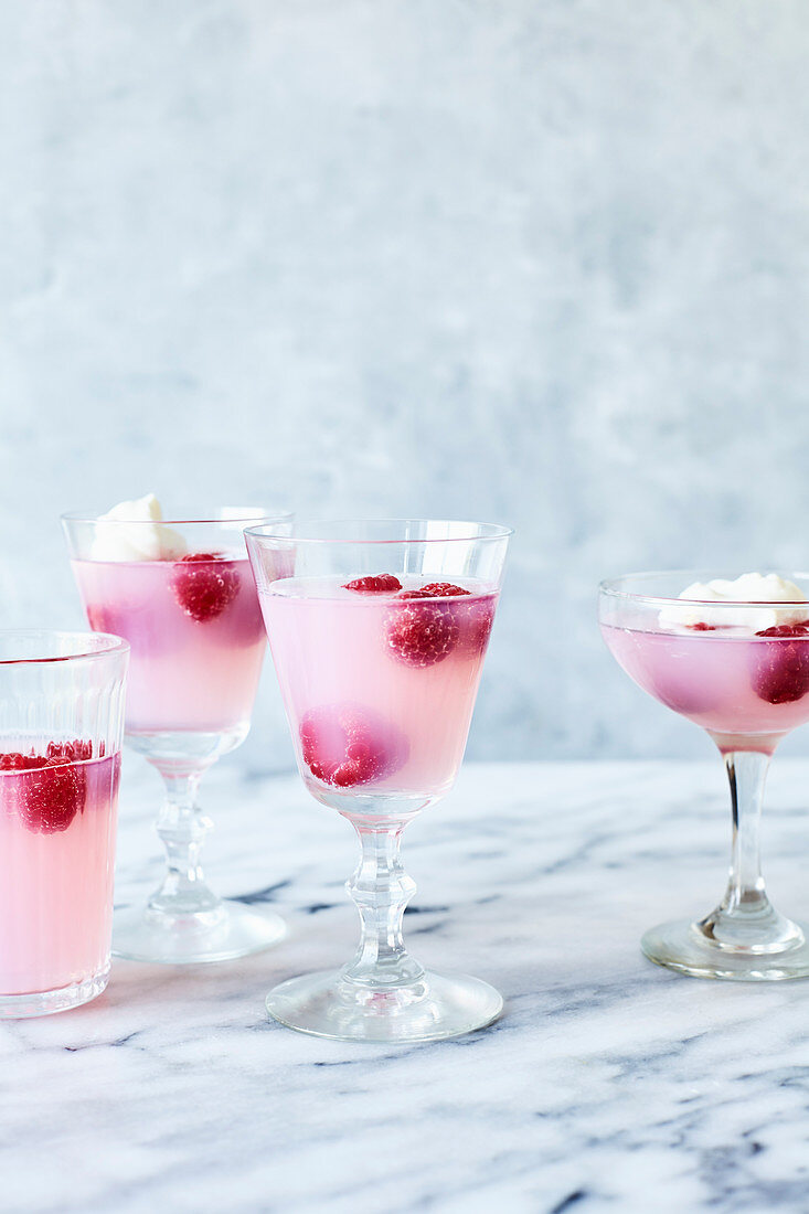 Pink lemonade jelly with raspberries and cream on light marble background