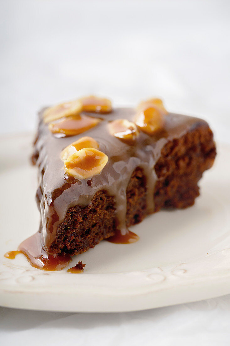 Close up of a piece of brownie cake with salted caramel and roasted peanuts