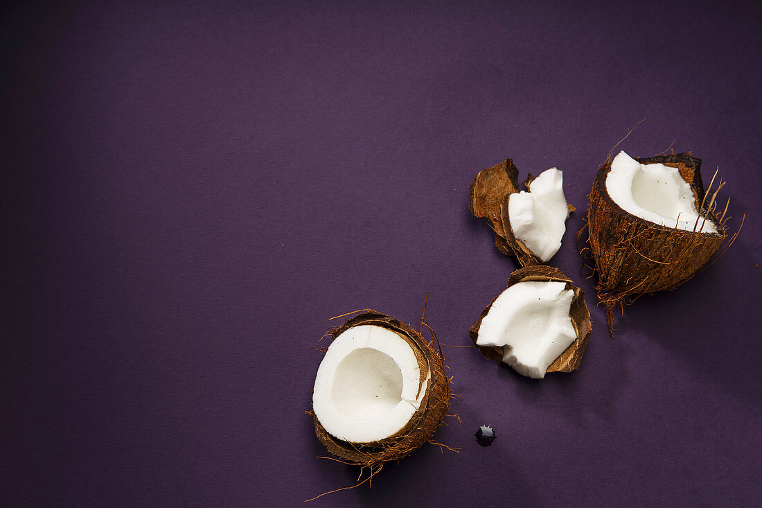 Cracked coconut arranged on dark purple background