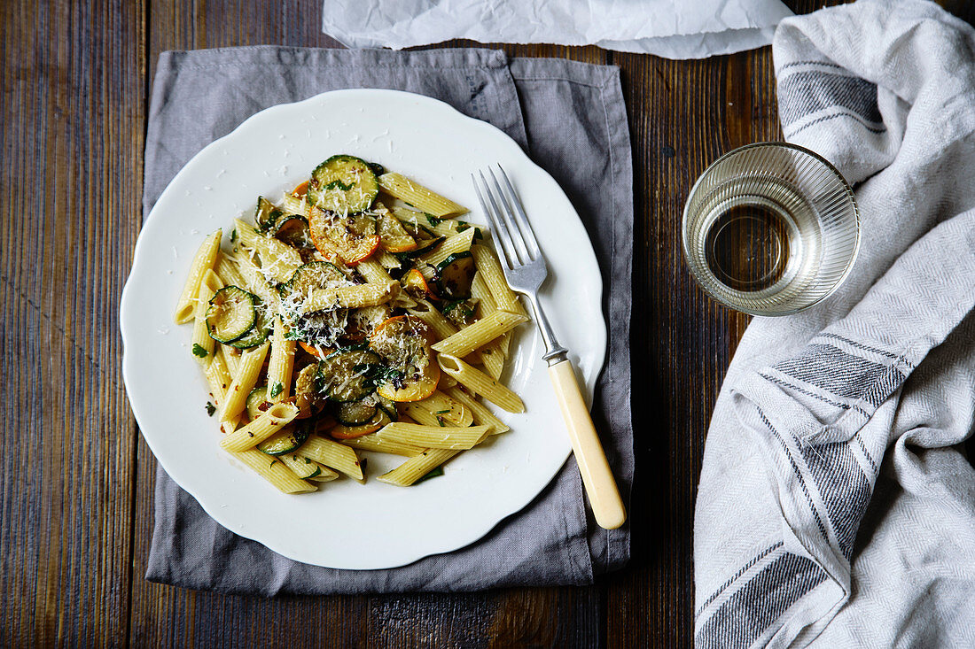 Pasta with zucchini and summer squash on wooden table