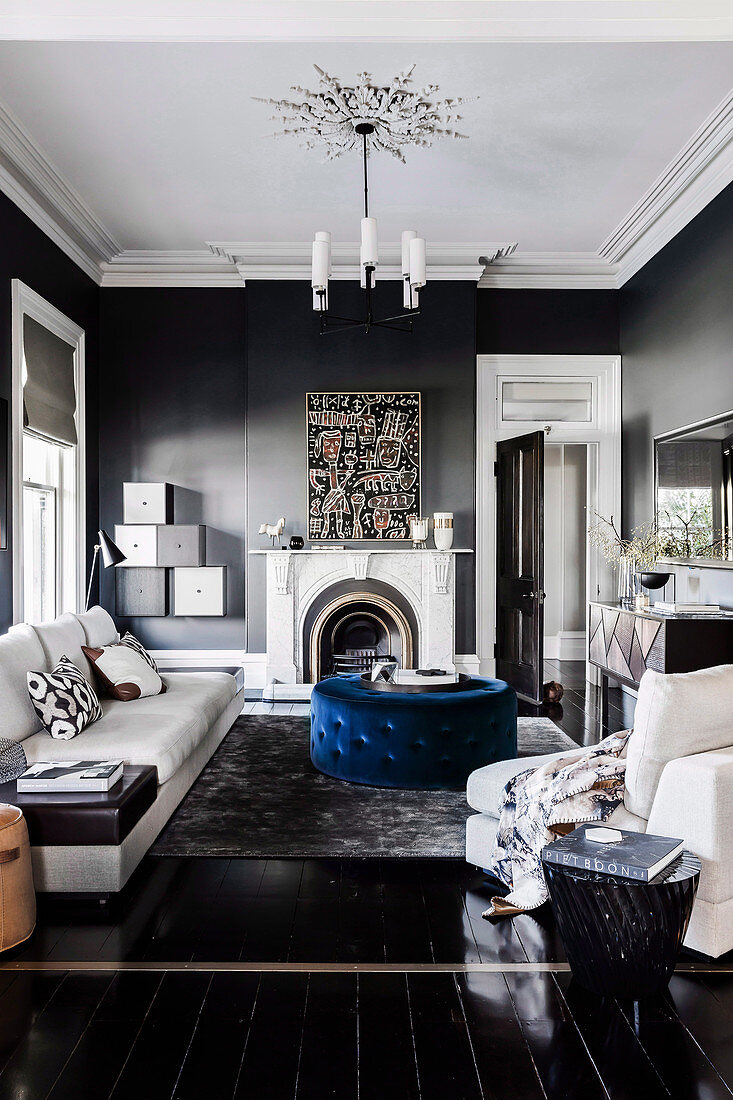 Light sofa set, blue upholstered table and fireplace in the living room with dark gray walls and black floorboards