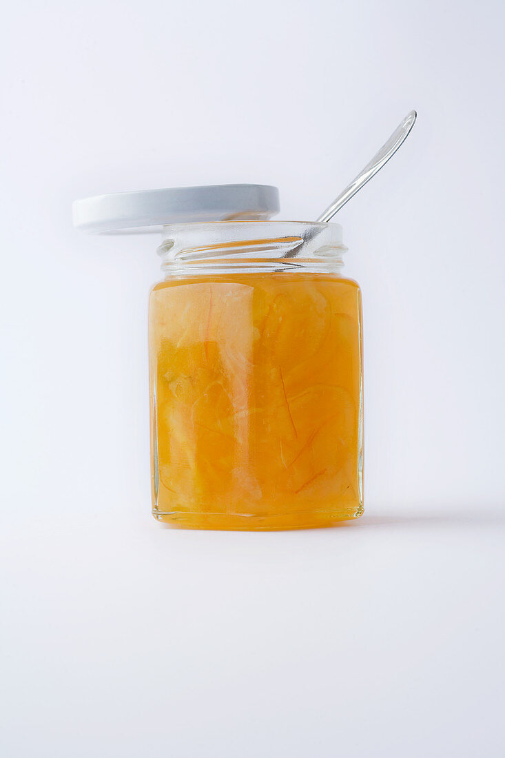 Ein Glas Mandarinenmarmelade vor weißem Hintergrund