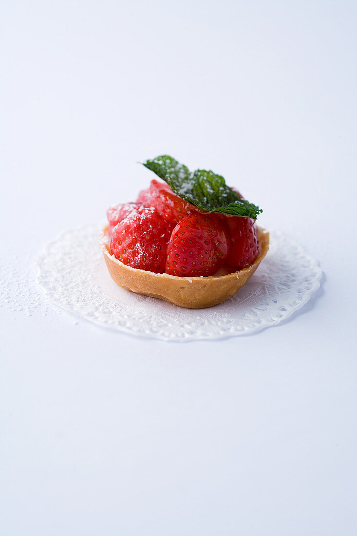 Ein Mini-Tartelett mit Erdbeeren vor weißem Hintergrund