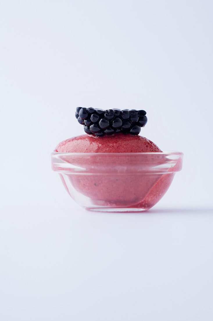 Blackberry sorbet in a glass bowl against a white background