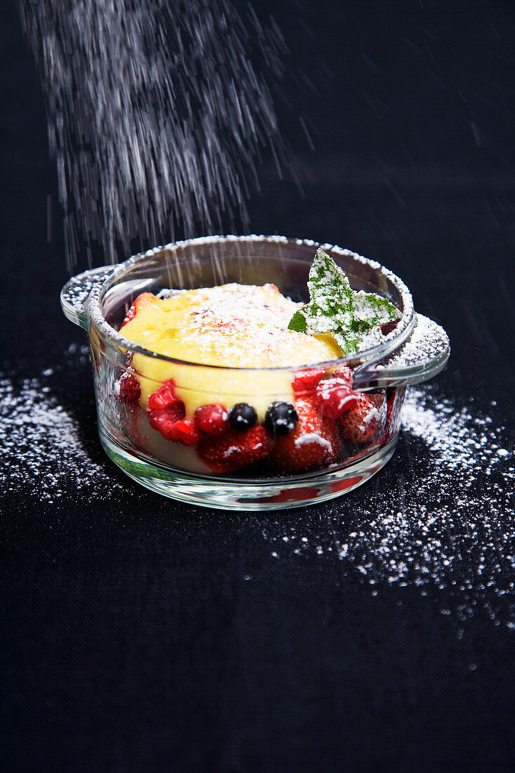 Dessert with berries and peaches dusted with powdered sugar